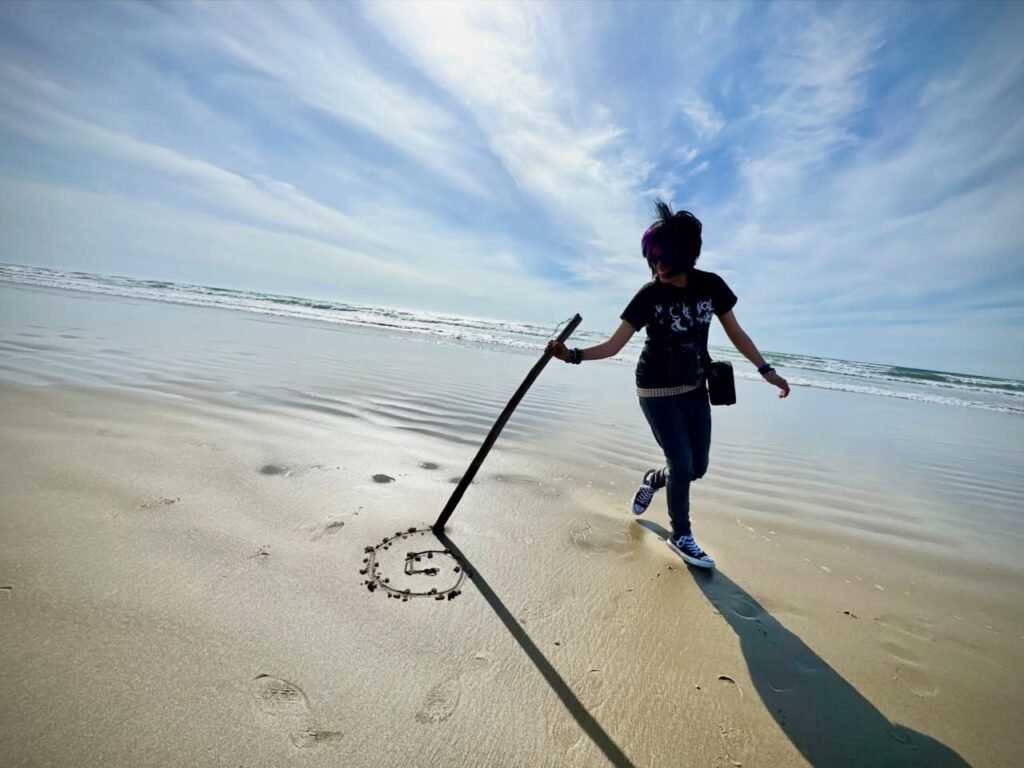 A person runs along the beach with a stick creating a visual trick on the sand.