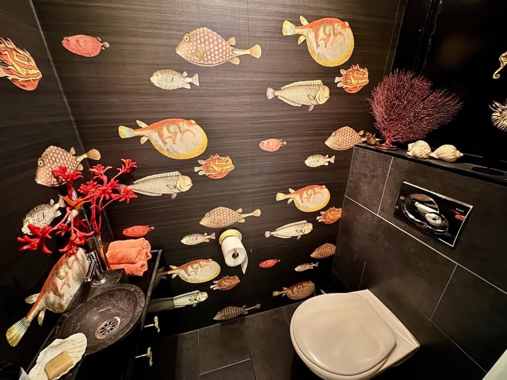 A creatively decorated restroom with fish-themed wallpaper.