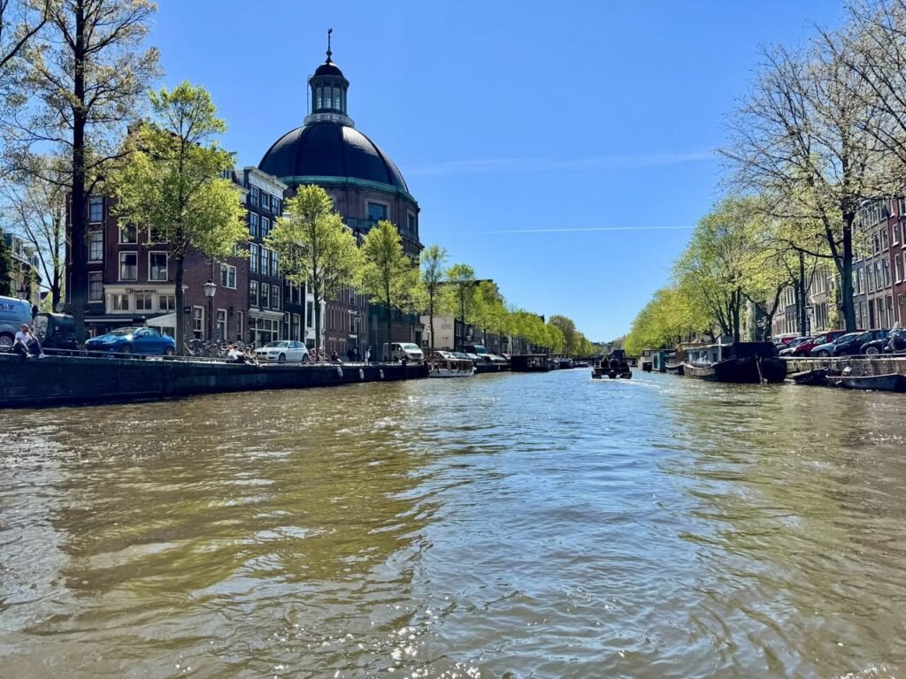 A view of a Dutch canal with historic buildings and spring trees.