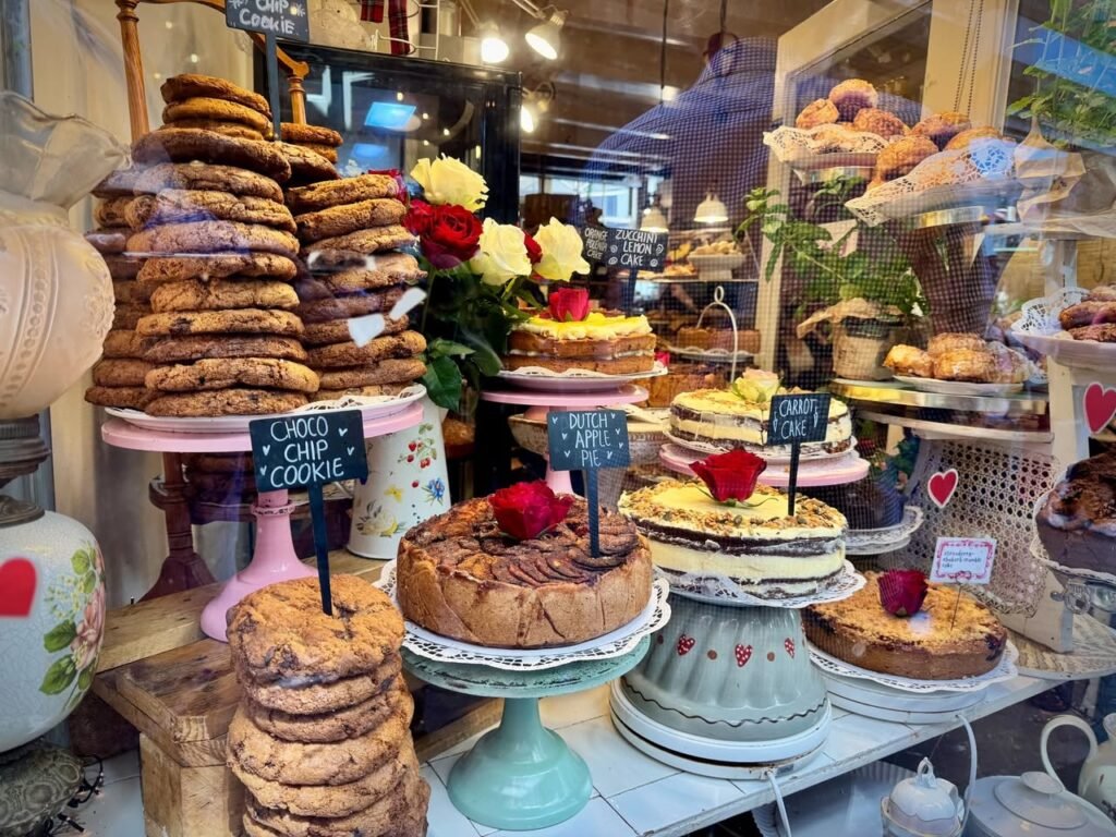 Elegant display of cheesecakes and chocolate chip cookies on ceramic stands, accented with fresh flowers.