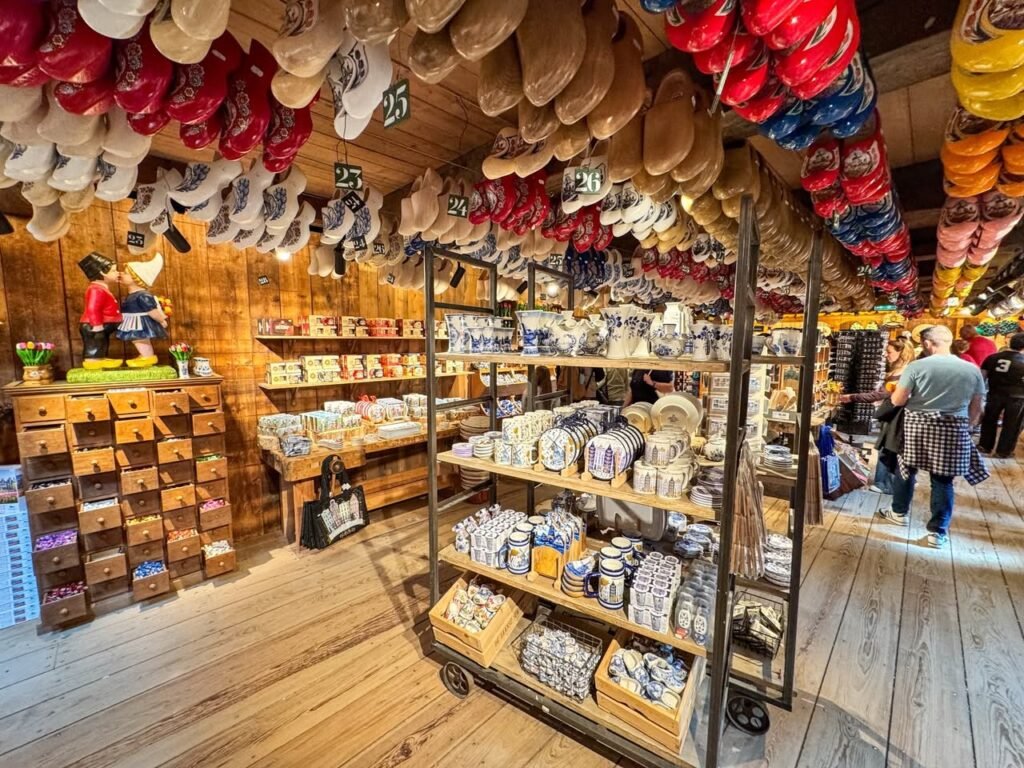 A display of colorful wool boots and traditional garments hanging in a wooden souvenir shop with shelves of merchandise below.
