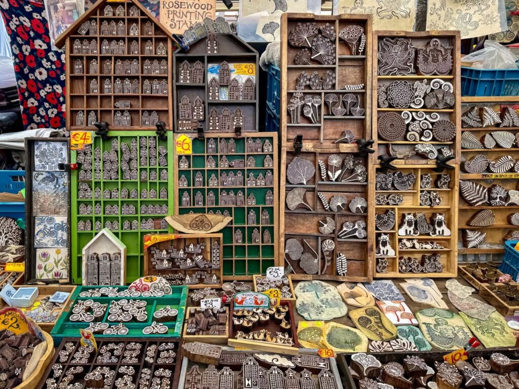 A bustling market stall with wooden shelving units displaying various decorative items and crafts.