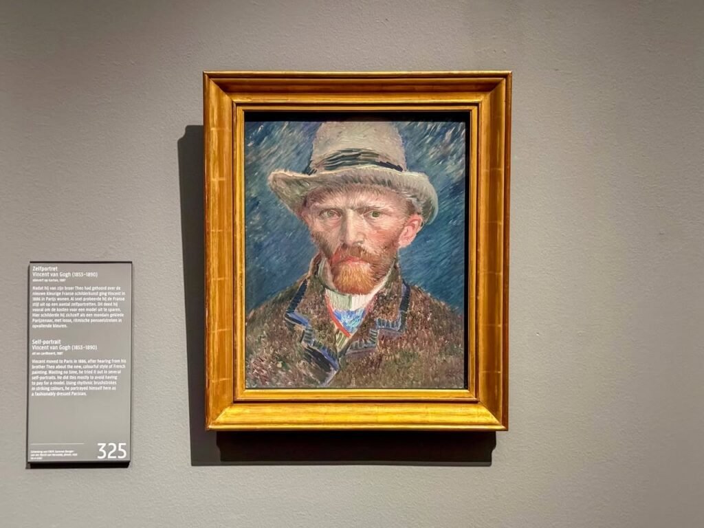 A photo of a framed portrait of a man in a hat displayed in a museum, with informational placards to the side.