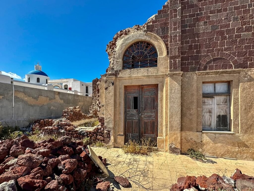 Old stone ruins featuring an arched window and surrounded by exposed red rocks.