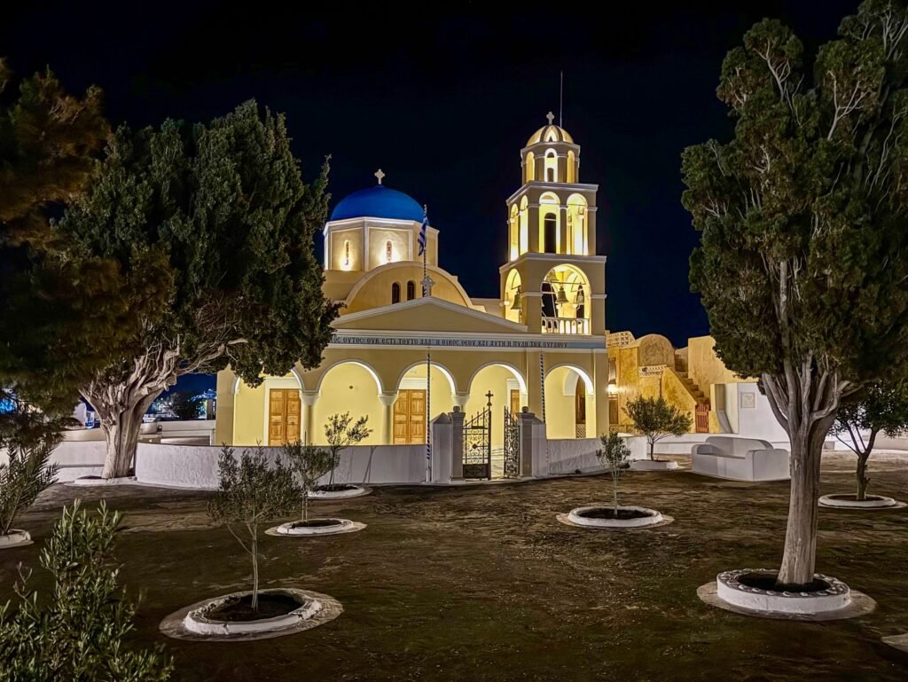 A beautiful church illuminated at night, featuring a blue dome and a bell tower against the dark sky.