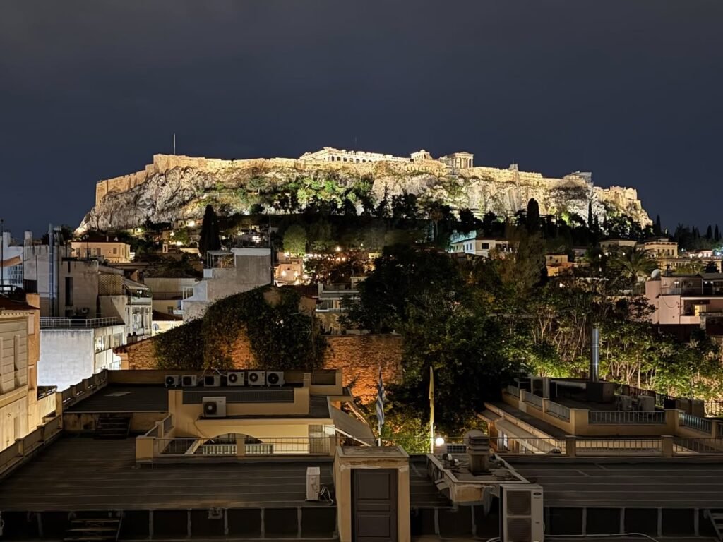 The illuminated Acropolis of Athens stands majestically above the city at night.