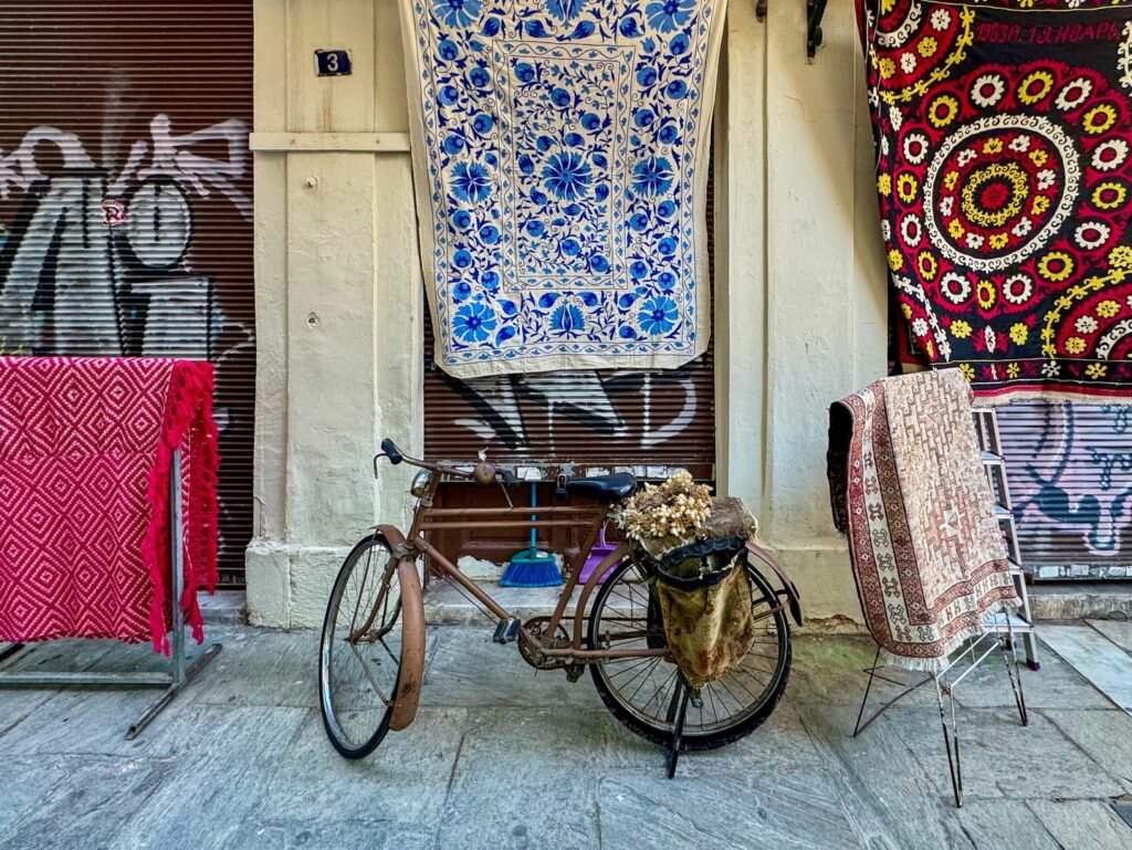 Vintage Bicycle and Patterned Textiles on Cobblestone Street