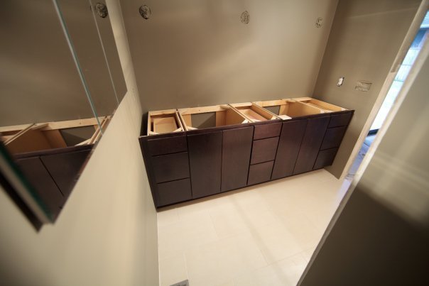 A view of dark wood vanity drawers and open wooden tops during a bathroom renovation. The countertop has not been installed yet.