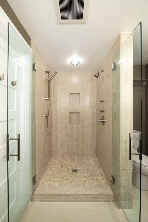 A beautifully tiled walk-in shower featuring glass walls and a step-in design.