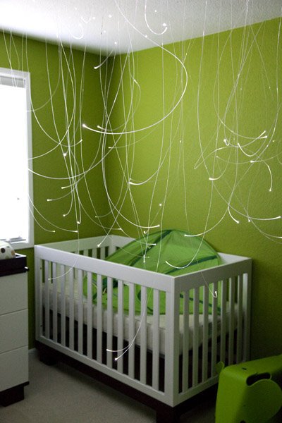 A nursery featuring a white crib, lime green walls, and decorative string lights.