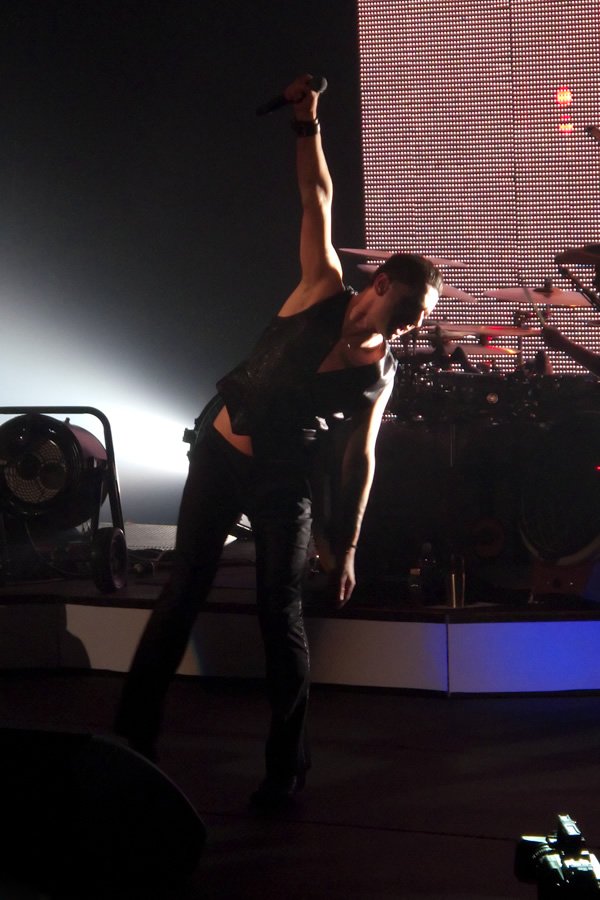 A performer captivates the audience with dynamic movements under vibrant stage lighting in an electrifying night concert setting.
