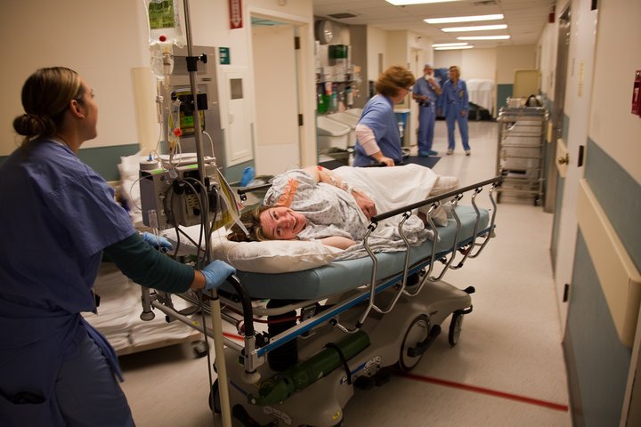 A patient is moved through a hospital corridor while medical staff attend to their care.