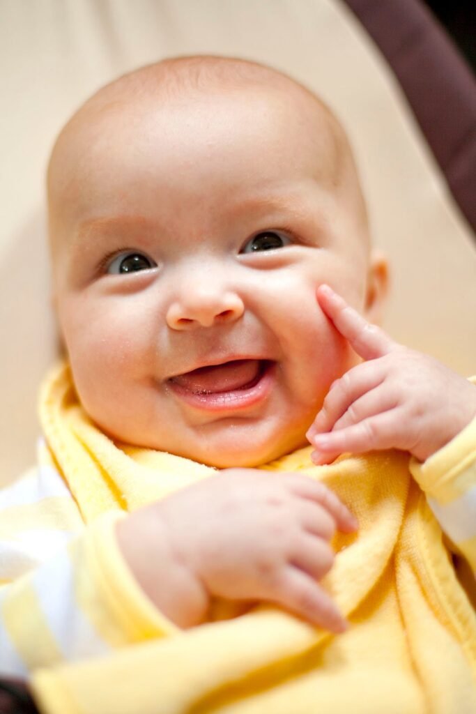 Close-up of a happy baby in a yellow outfit.