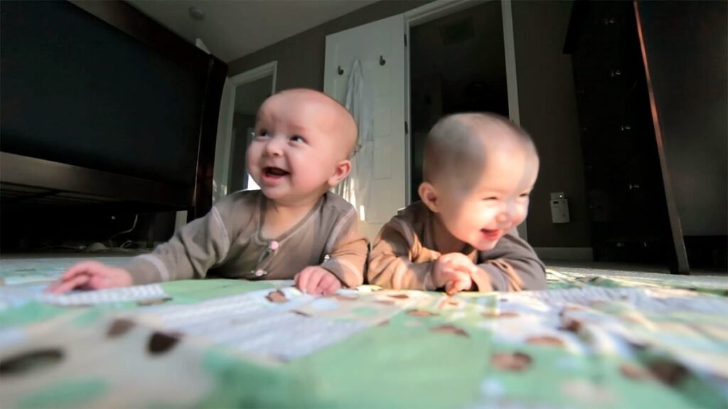 A baby and a child lean over a patterned table, looking happy and engaged.