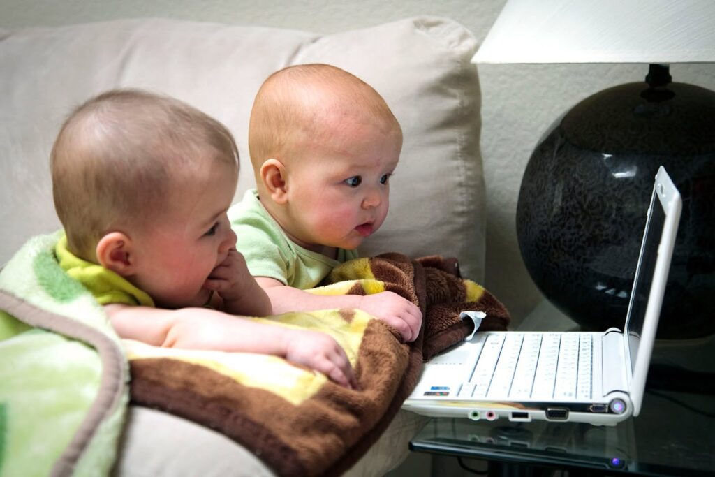 Twin babies watching a laptop screen together.