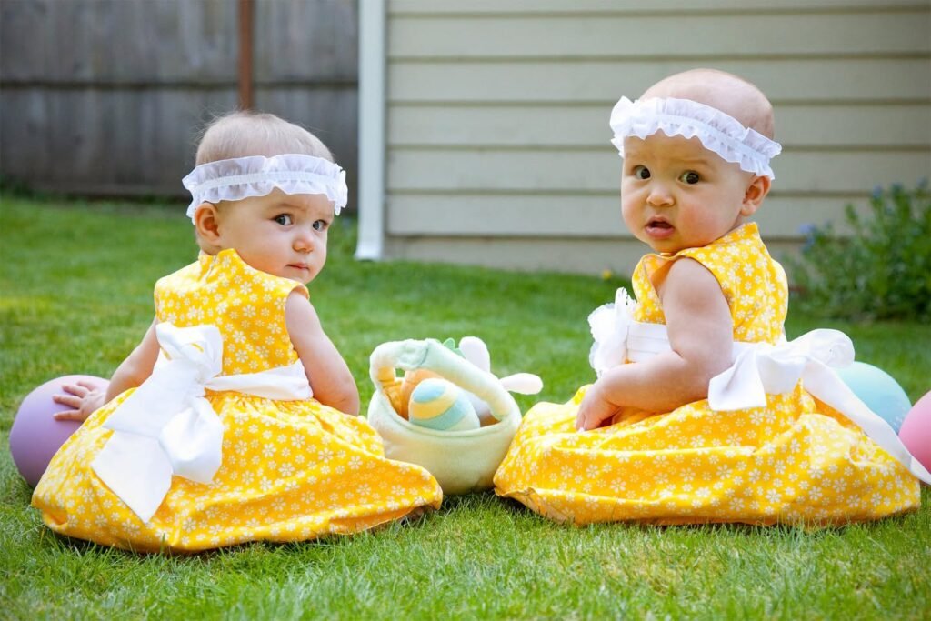 Babies in yellow Easter outfits sitting on the grass with a basket of eggs. A close-up of a baby wearing a white headband.