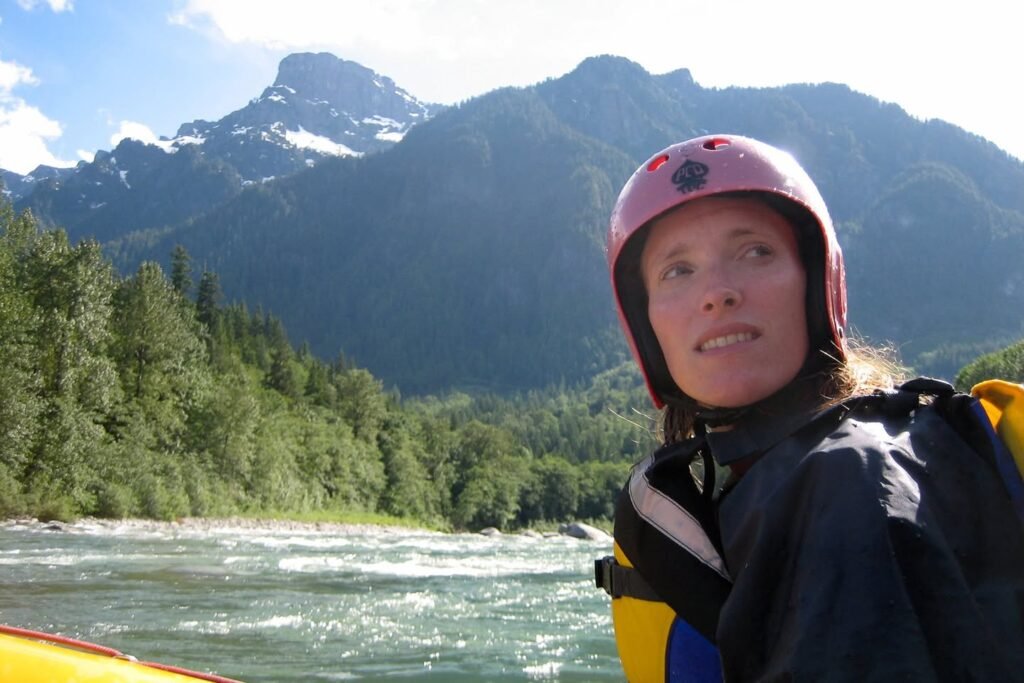 A person rafting on a river surrounded by lush forests and mountains.
