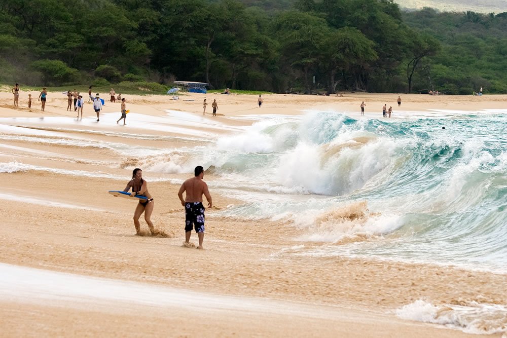 Surfers enjoy the crashing waves of Pipe