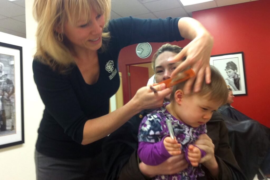 A young child getting their hair braided by an adult in a home setting.