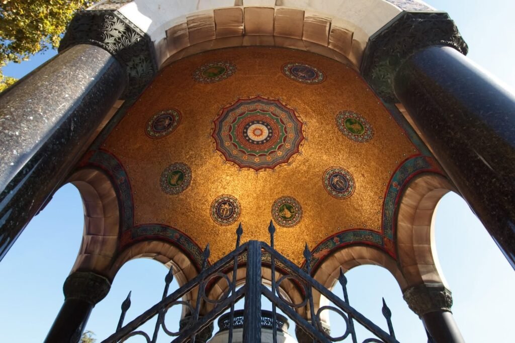 A beautifully tiled gazebo with intricate mosaic patterns viewed from the ground looking up. This architectural element displays detailed craftsmanship in its design.