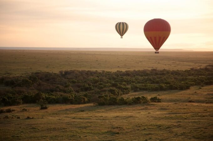 Hot air balloons floating over a vast landscape during a hot air balloon safari.