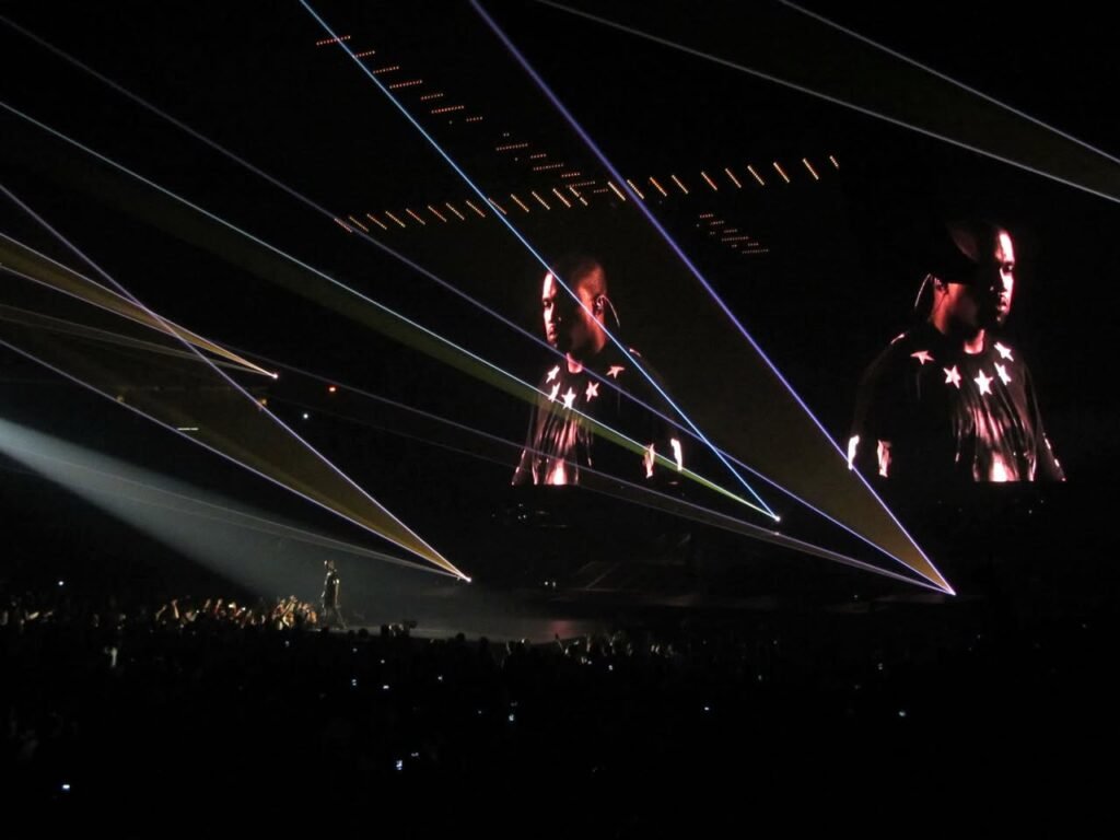 Performers under beams of red and blue stage lighting at a live concert.