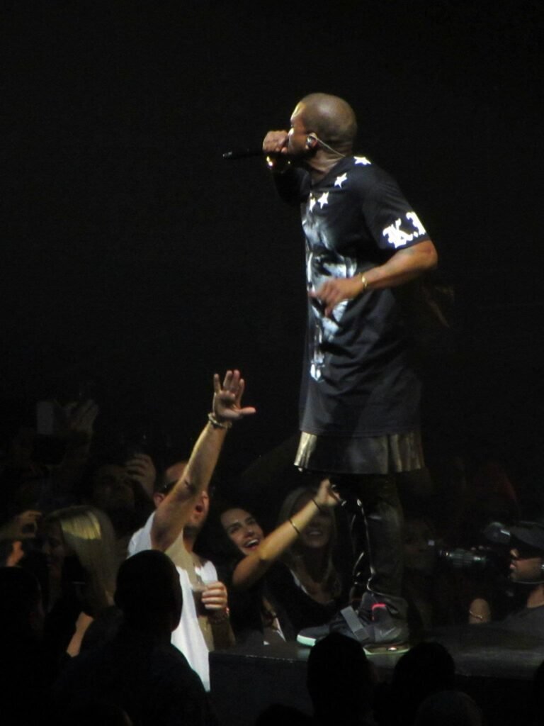 A performer singing on stage at night with an engaged audience reaching up.