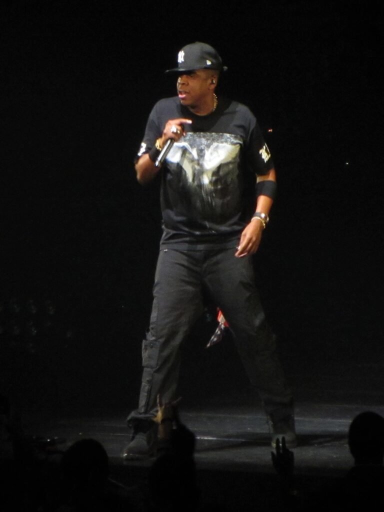 A performer in black attire holding a microphone on a dimly lit stage. Headshots and full-body views show a solo artist captivating the audience.