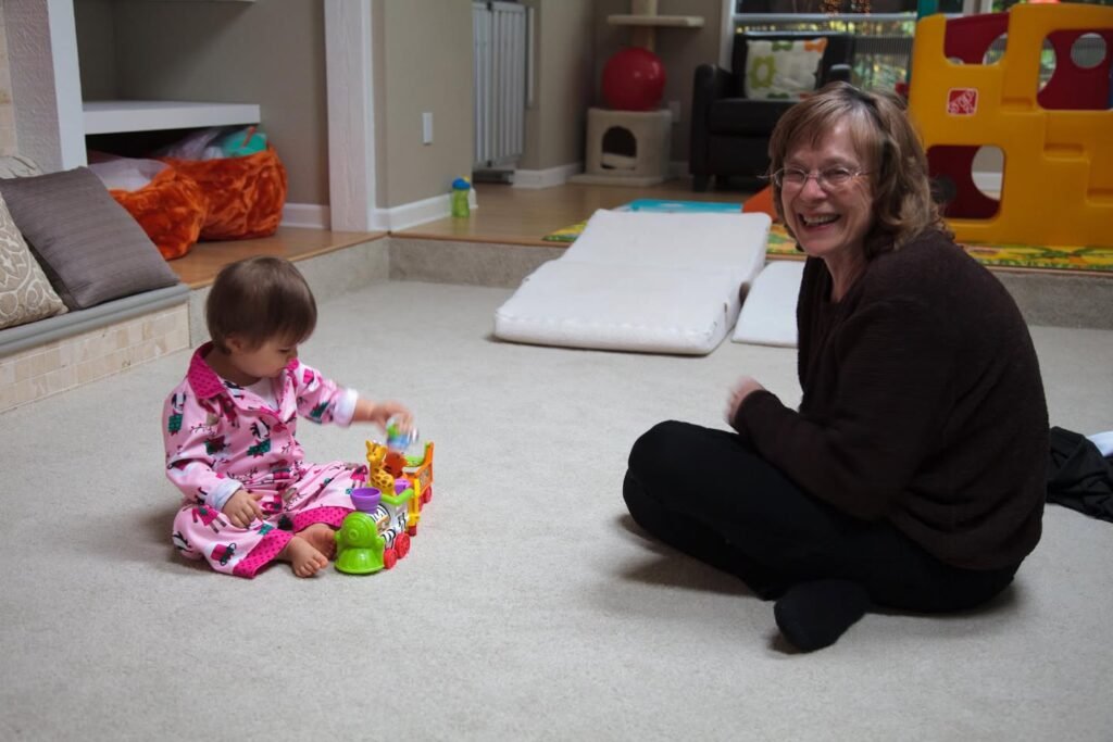 A cozy indoor scene featuring a child in pajamas playing with colorful blocks while a smile stands nearby on the carpet.