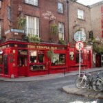 A close-up of the red brick facade of The Temple Bar pub in Dublin, with bicycles parked on the cobblestone street.
