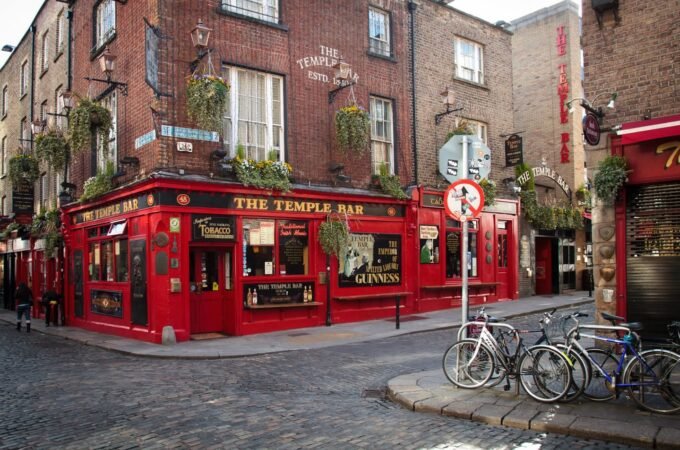A close-up of the red brick facade of The Temple Bar pub in Dublin, with bicycles parked on the cobblestone street.