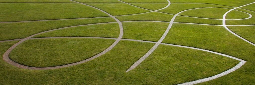 Aerial view of winding paths creating geometric patterns in a vibrant green field.