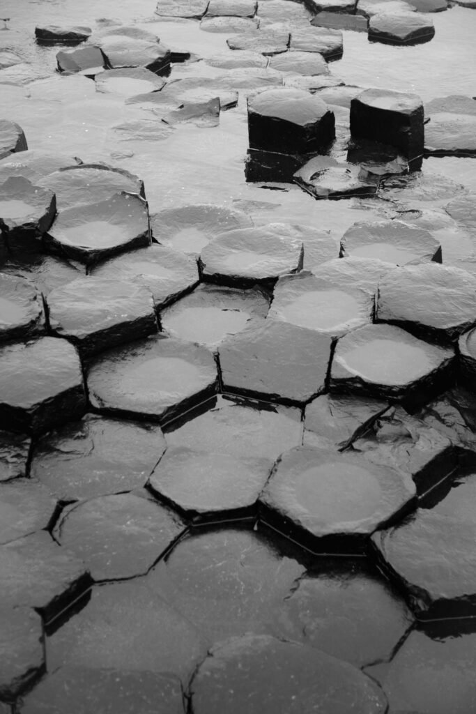 Detailed black and white photographs of hexagonal basalt columns at a natural geological site.