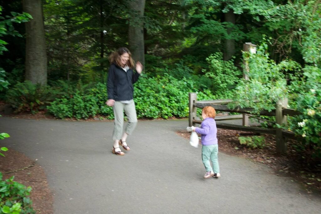 People enjoy a peaceful walk on a paved path through a lush forest in the Pacific Northwest.