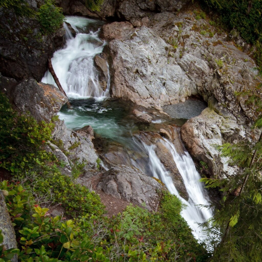 A series of small waterfalls cascading down rocky terrain surrounded by lush green vegetation.