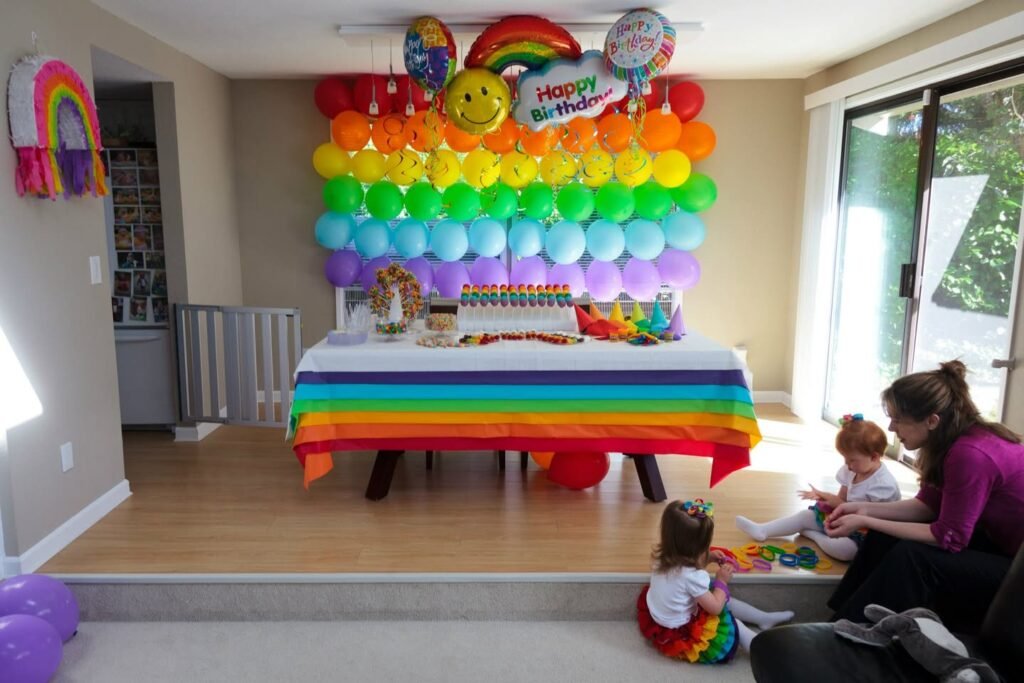 A child-friendly birthday party space decorated with a rainbow balloon wall and themed table setting.