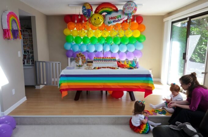 A child-friendly birthday party space decorated with a rainbow balloon wall and themed table setting.