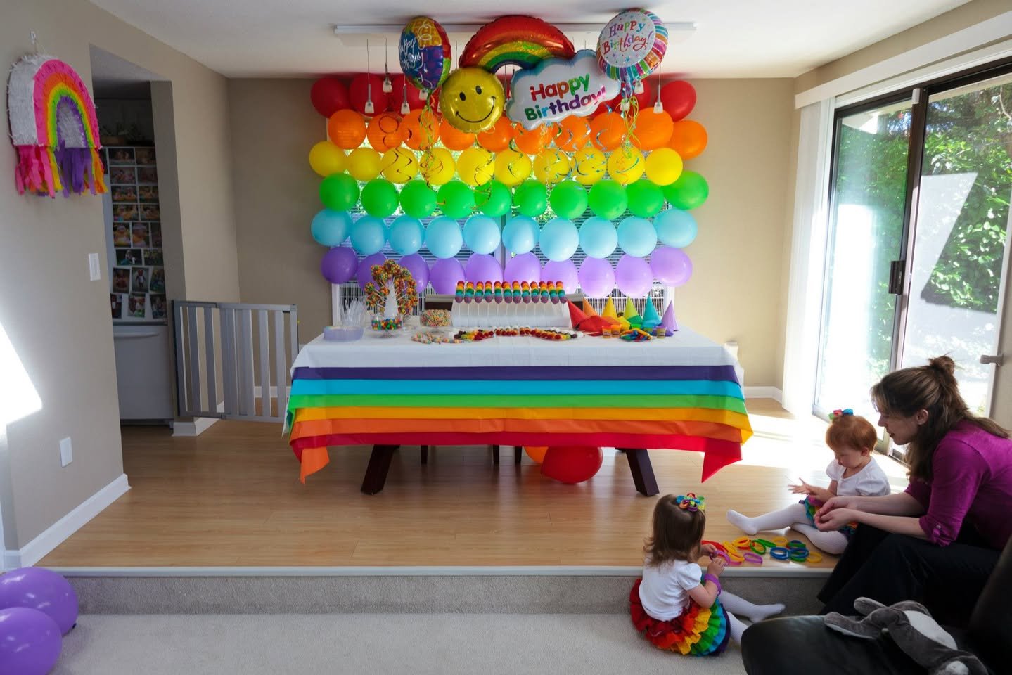 A child-friendly birthday party space decorated with a rainbow balloon wall and themed table setting.
