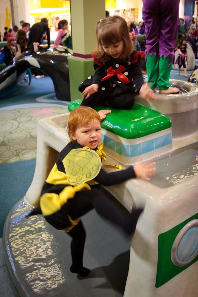 Children in costumes playing at an interactive water feature in a mall.