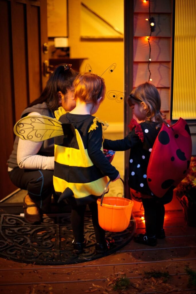 Children in Halloween costumes stand on a porch.