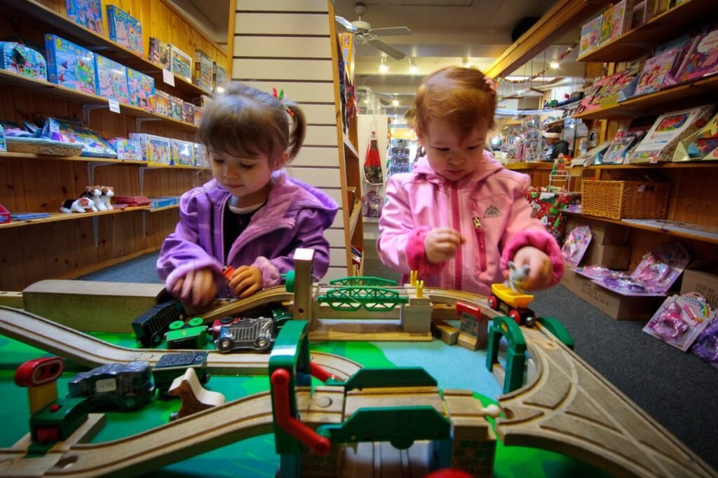 A group of children plays with a wooden train set in a store.