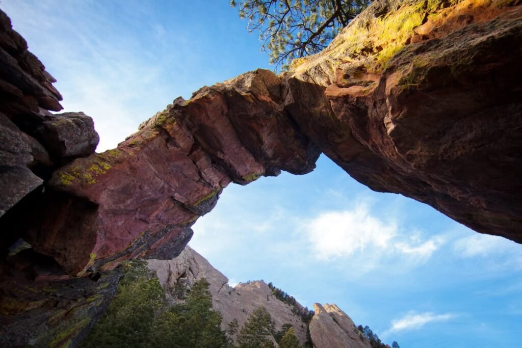 Natural rock arch framing mountain range under a blue sky.