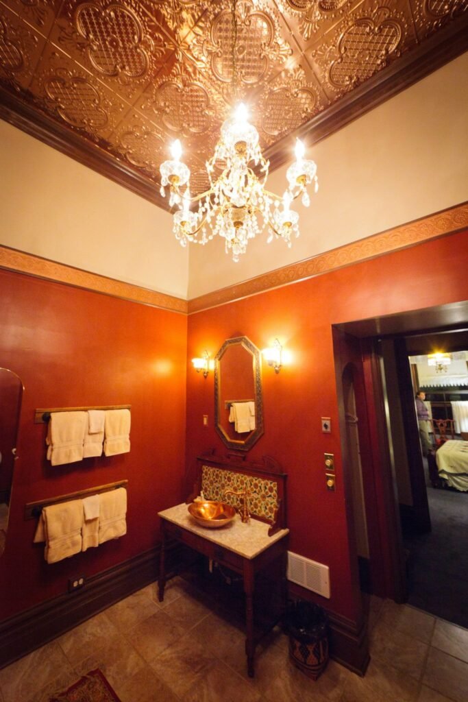 Rich red walls and intricate ceiling design create a luxurious hotel room atmosphere.