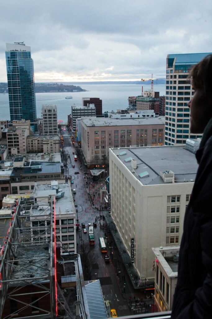 A panoramic cityscape of Vancouver viewed from the SkyTrain, featuring skyscrapers, streets, and the ocean in the background.