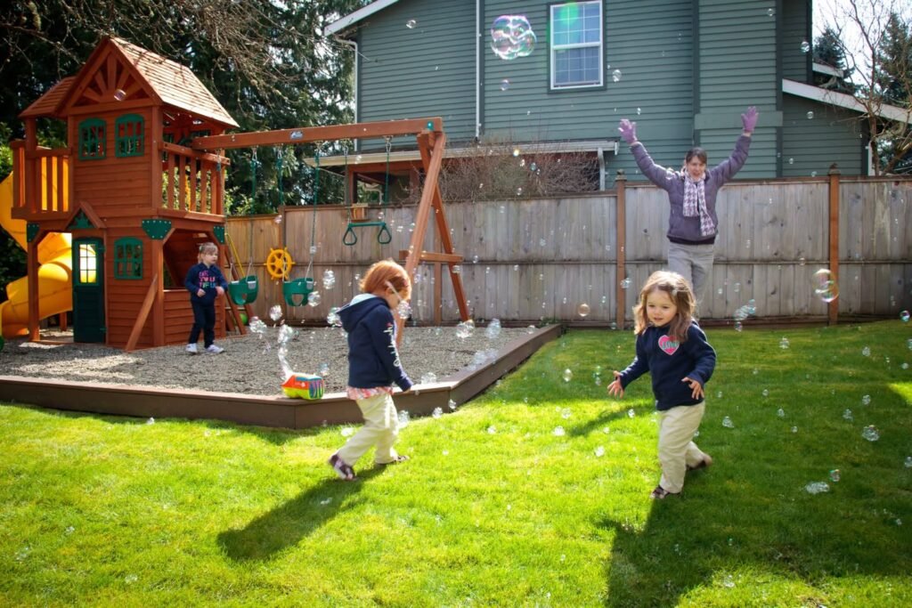 Children playing outside near a wooden playhouse and grass lawn.