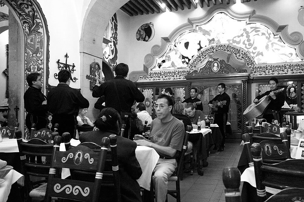 A black and white photo of a traditional Belarusian restaurant with ornate decor and patrons dining at tables.