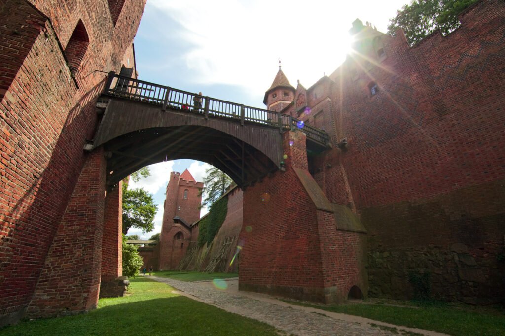 A striking view of a medieval fortress wall with arched walkways and towers, showcasing historical architecture under sunlight.