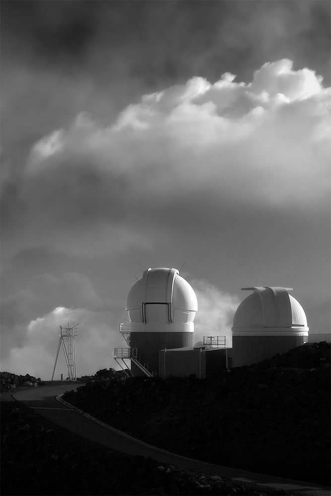 Black and white photo of observatory domes under a cloudy sky.