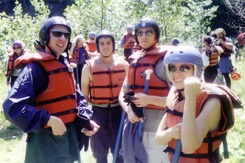 A group of people wearing helmets and life vests outdoors, ready for an adventure activity.