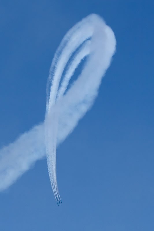 An airplane performing a loop in the sky with a trail of white smoke.